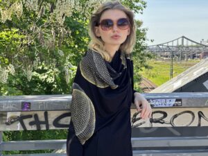 Model mit Sonnenbrille und Dreieckstuch blickt in die Kamera